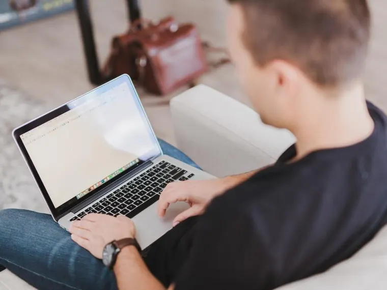 Homem com notebook e computador na sala