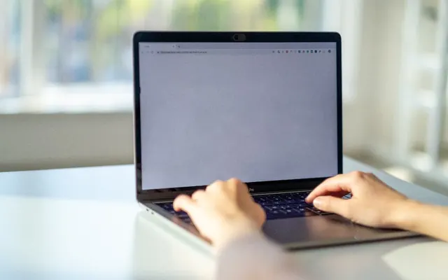 Mãos com notebook e computador no escritório