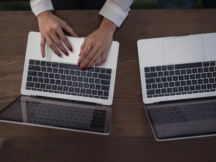 Mulher com celular e notebook no escritório